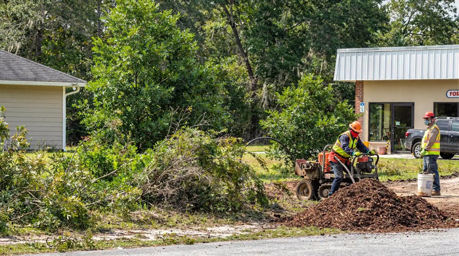 Crew running a wood chipper beside a brush pile on a residential lot in Chipley, Florida
